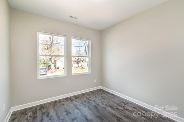 unfurnished room with dark wood finished floors, baseboards, and visible vents