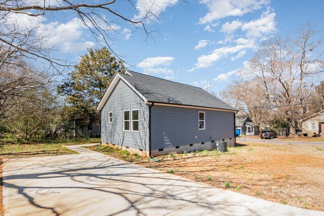 rear view of house featuring crawl space, cooling unit, and roof with shingles