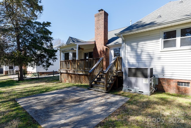 back of house with crawl space, a yard, a chimney, and a patio area