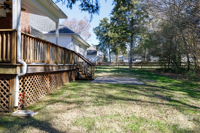 view of yard with a wooden deck, stairs, and fence