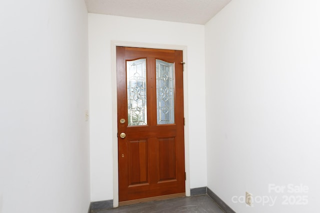 doorway to outside featuring a textured ceiling and baseboards