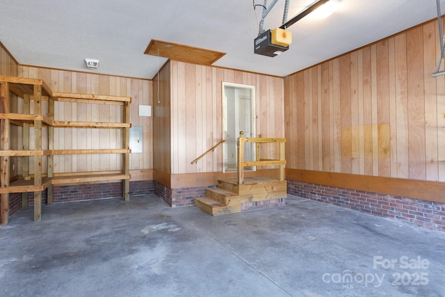 garage featuring visible vents, wood walls, and a garage door opener