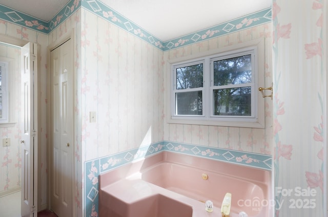 bathroom featuring a bath and wallpapered walls