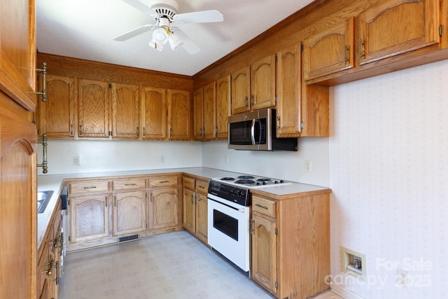 kitchen featuring white electric range oven, stainless steel microwave, light floors, and brown cabinets