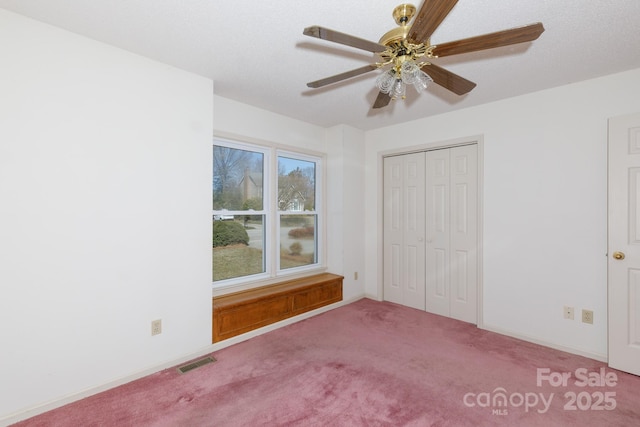 unfurnished bedroom with visible vents, baseboards, a ceiling fan, and carpet flooring