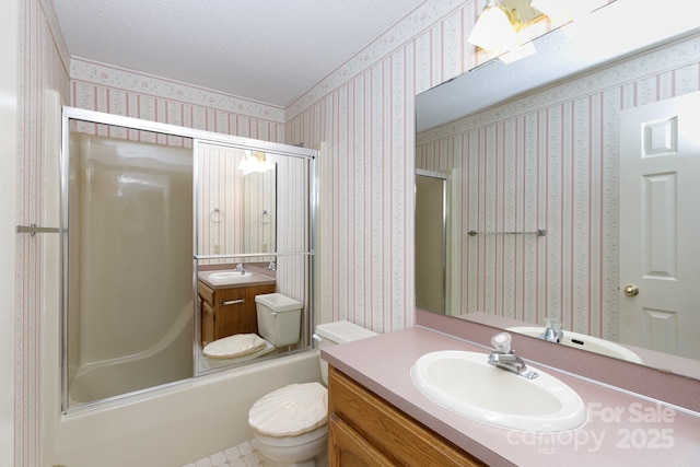 full bathroom with wallpapered walls, toilet, vanity, and a textured ceiling