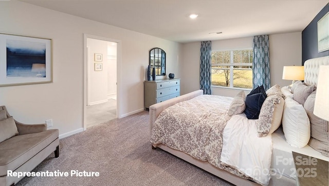 carpeted bedroom featuring visible vents, ensuite bathroom, and baseboards