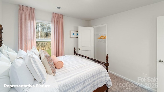 carpeted bedroom featuring visible vents, baseboards, and a spacious closet