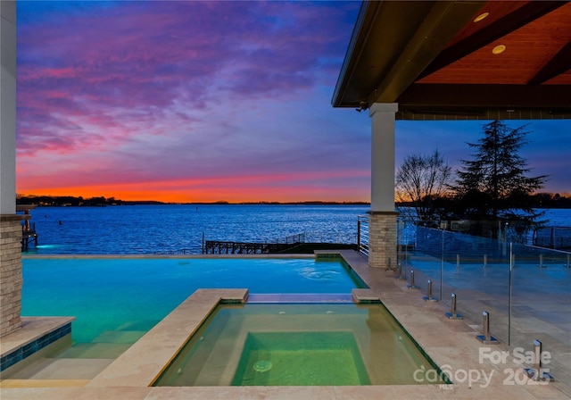 18601 Bluff Point Rd, Cornelius, NC 28031 - pool at dusk featuring a pool with connected hot tub, fence, and a water view