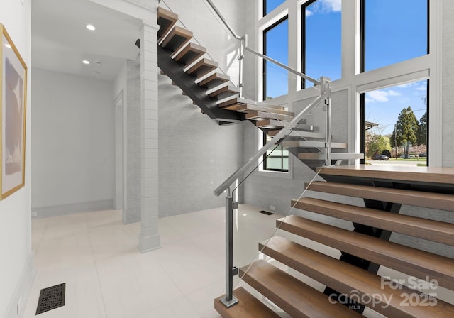 18601 Bluff Point Rd, Cornelius, NC 28031 - staircase with tile patterned floors, visible vents, a healthy amount of sunlight, and a high ceiling