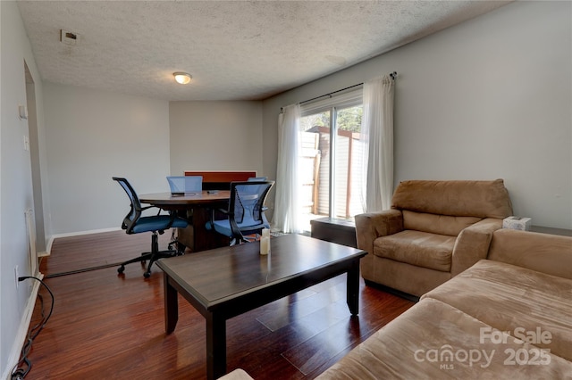 living area with wood finished floors, baseboards, and a textured ceiling