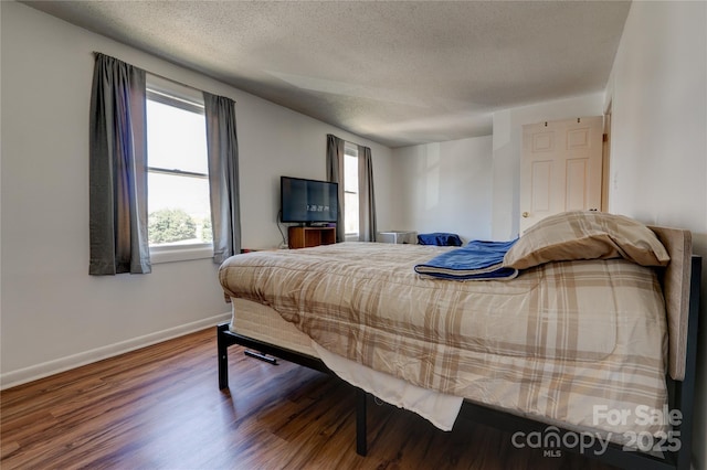 bedroom featuring baseboards, a textured ceiling, and wood finished floors