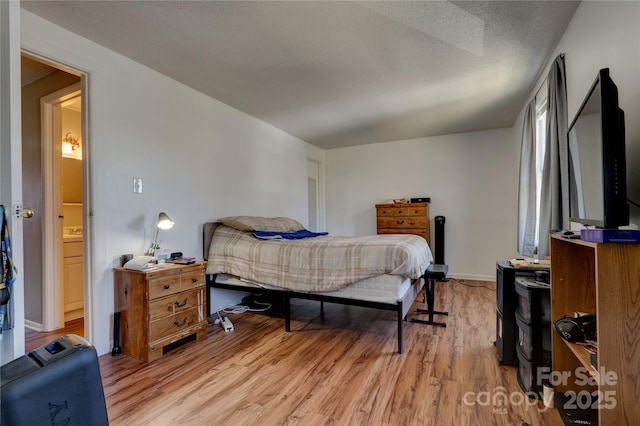 bedroom featuring a textured ceiling, light wood-type flooring, and baseboards