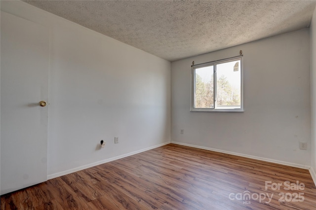 empty room featuring baseboards, a textured ceiling, and wood finished floors