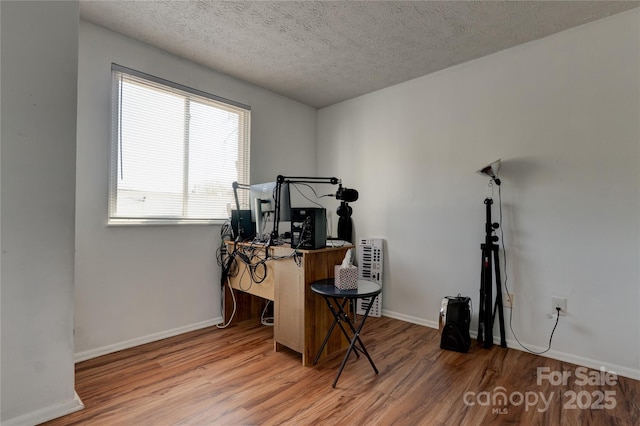 home office featuring baseboards, a textured ceiling, and wood finished floors