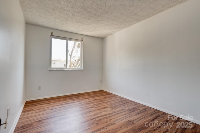 unfurnished room with wood finished floors, baseboards, and a textured ceiling