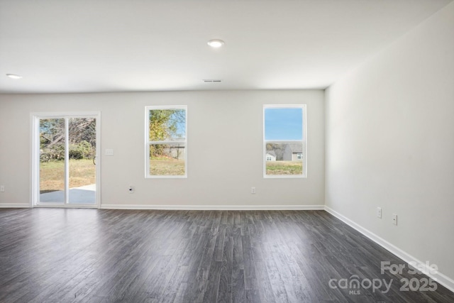 unfurnished room with visible vents, dark wood-type flooring, and baseboards