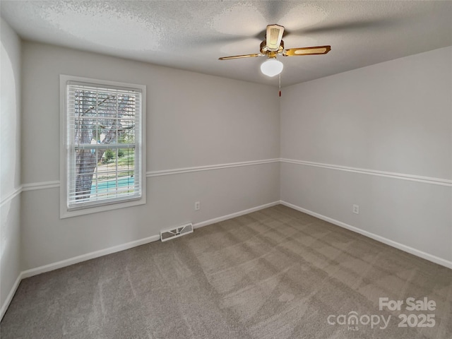 empty room featuring visible vents, a ceiling fan, a textured ceiling, carpet flooring, and baseboards