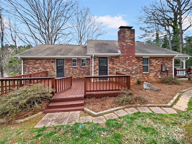 back of house featuring brick siding, a wooden deck, and a chimney