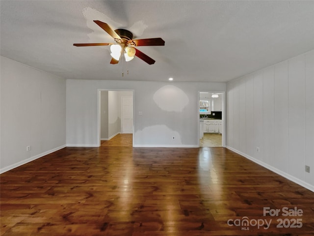 unfurnished living room with ceiling fan, baseboards, and wood finished floors