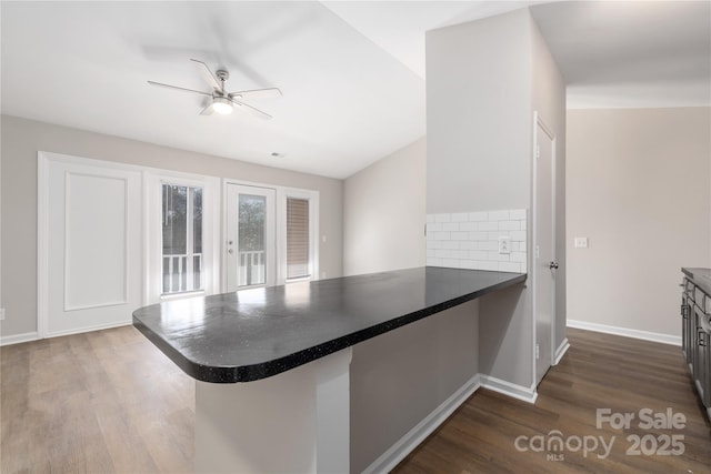 kitchen featuring dark countertops, dark wood finished floors, a peninsula, and ceiling fan