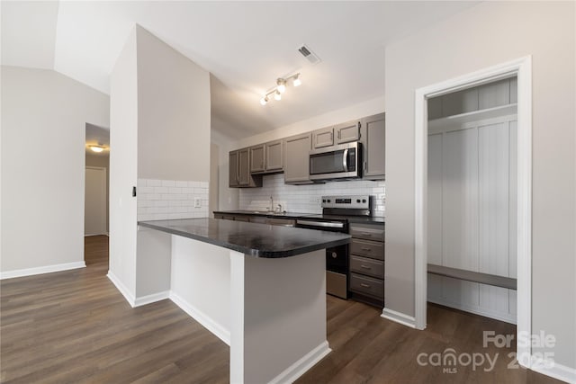 kitchen with visible vents, dark countertops, appliances with stainless steel finishes, a peninsula, and vaulted ceiling