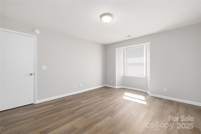 unfurnished room with wood finished floors and baseboards