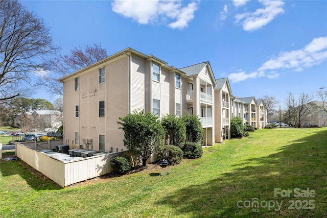 view of side of home with central AC unit, a lawn, and a residential view