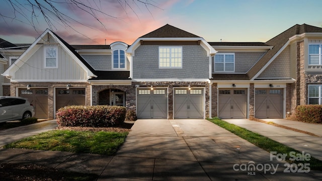 view of front of house with stone siding, board and batten siding, concrete driveway, and a garage