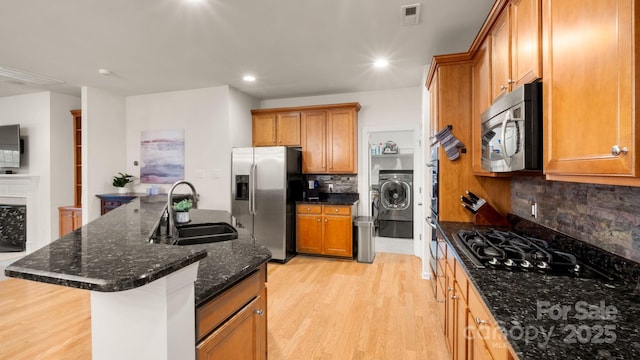 kitchen with brown cabinetry, visible vents, light wood finished floors, a sink, and stainless steel appliances