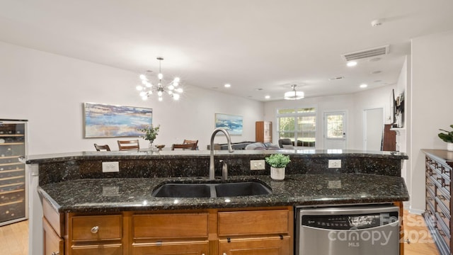 kitchen with brown cabinetry, a sink, stainless steel dishwasher, open floor plan, and a chandelier