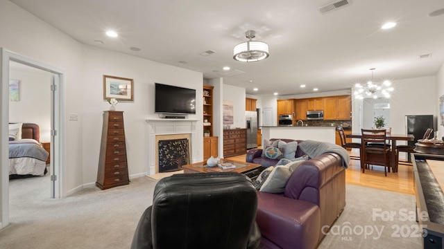 living area featuring baseboards, visible vents, recessed lighting, a fireplace, and a chandelier