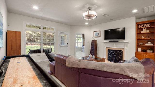 living area with a high end fireplace, visible vents, and recessed lighting