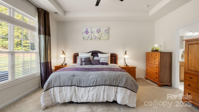 bedroom with visible vents, baseboards, ceiling fan, light colored carpet, and a tray ceiling