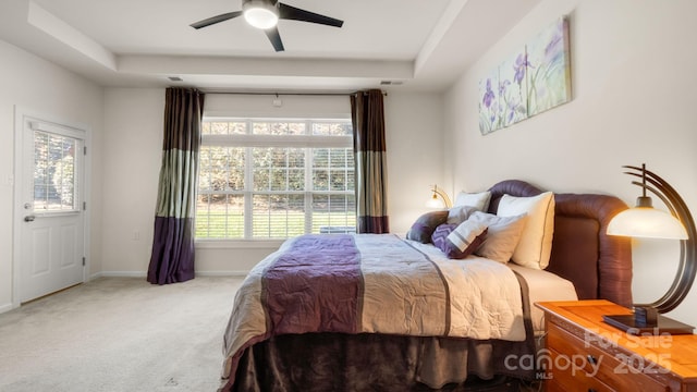 bedroom featuring ceiling fan, baseboards, a tray ceiling, and carpet floors