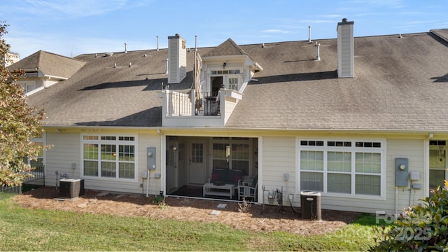 rear view of property featuring a balcony, central AC, a chimney, and a shingled roof