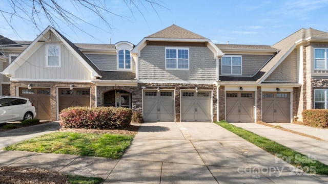 multi unit property featuring stone siding, driveway, and a garage