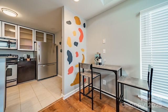 513 N Graham St Unit 3H, Charlotte, NC 28202 - kitchen featuring glass insert cabinets, baseboards, dark countertops, light wood-type flooring, and stainless steel appliances