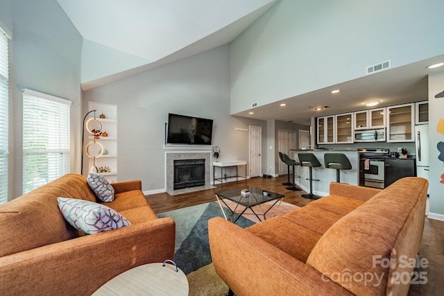 513 N Graham St Unit 3H, Charlotte, NC 28202 - living room with visible vents, baseboards, a tiled fireplace, dark wood finished floors, and high vaulted ceiling