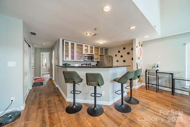 513 N Graham St Unit 3H, Charlotte, NC 28202 - kitchen with light wood-style flooring, dark countertops, a breakfast bar, and stainless steel appliances