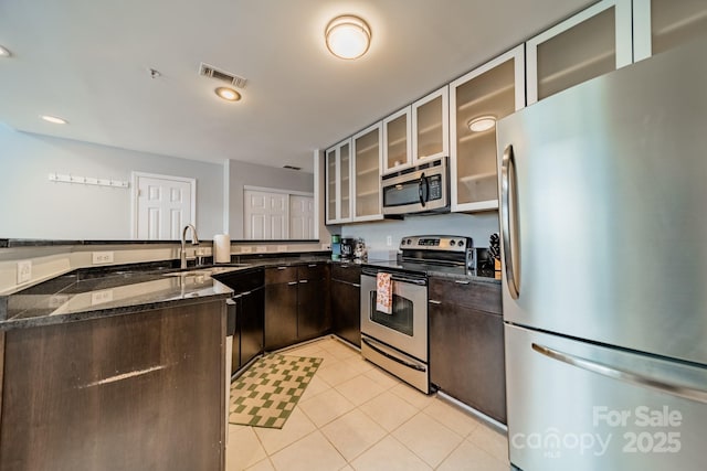 513 N Graham St Unit 3H, Charlotte, NC 28202 - kitchen with a peninsula, dark brown cabinets, light tile patterned flooring, appliances with stainless steel finishes, and a sink