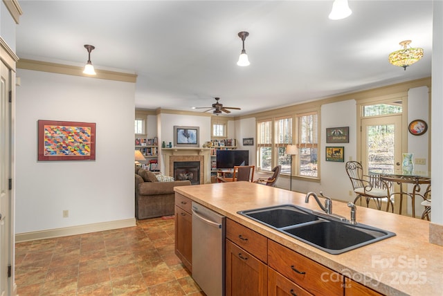 kitchen with brown cabinetry, a tile fireplace, a sink, pendant lighting, and stainless steel dishwasher