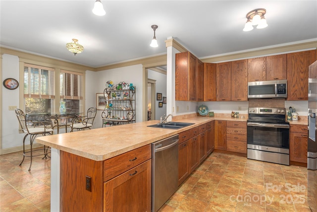 kitchen featuring crown molding, light countertops, brown cabinetry, stainless steel appliances, and a sink