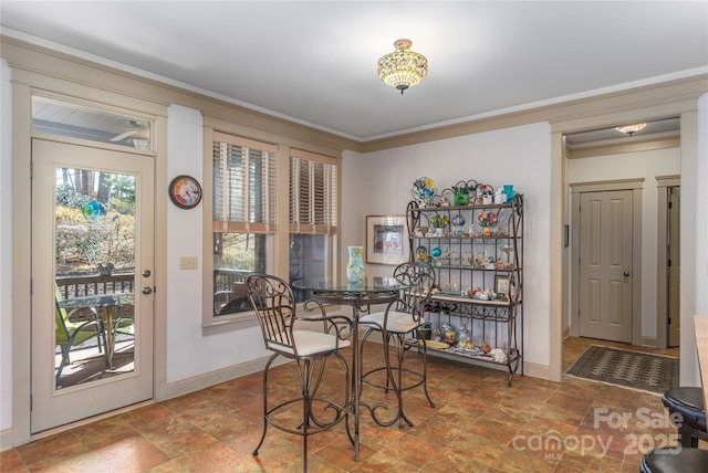 dining area with stone finish flooring, baseboards, and crown molding