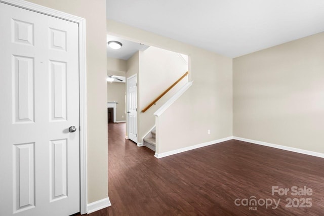 interior space featuring dark wood-type flooring, stairway, and baseboards