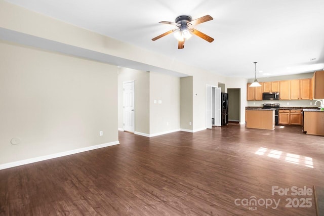 unfurnished living room featuring baseboards, dark wood-type flooring, and a ceiling fan