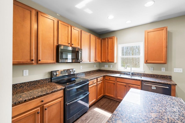 kitchen featuring a sink, dark wood-style floors, recessed lighting, stainless steel appliances, and dark stone counters