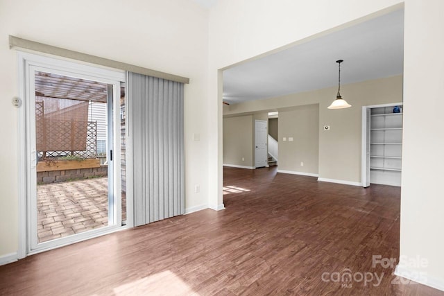 spare room with baseboards and wood finished floors