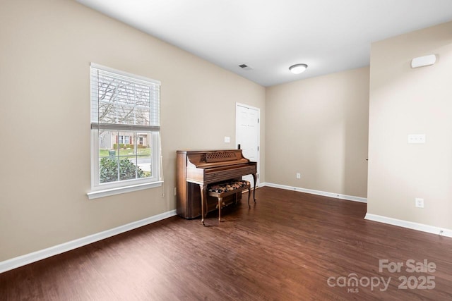 living area with baseboards, visible vents, and dark wood-style flooring