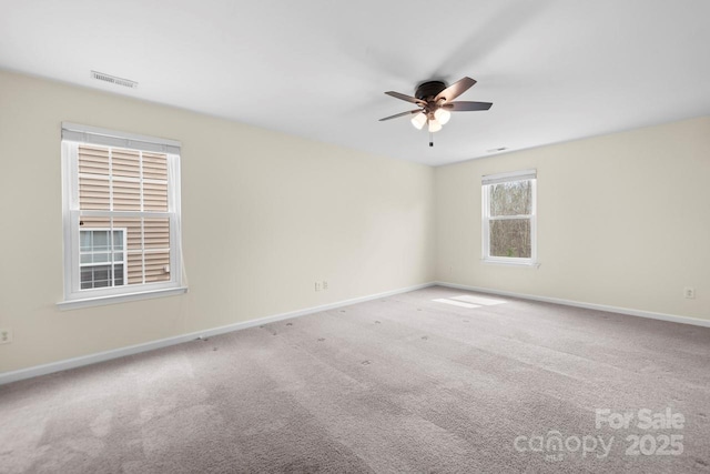 carpeted empty room featuring baseboards, visible vents, and ceiling fan